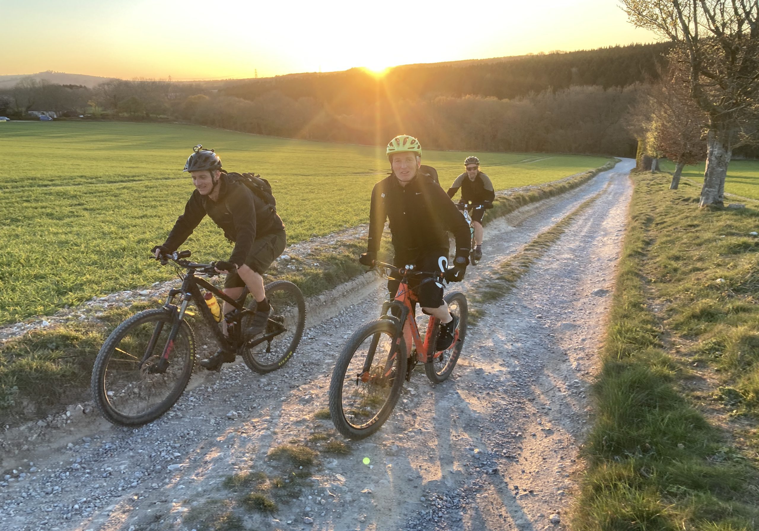 friends riding mountain bikes at sunset